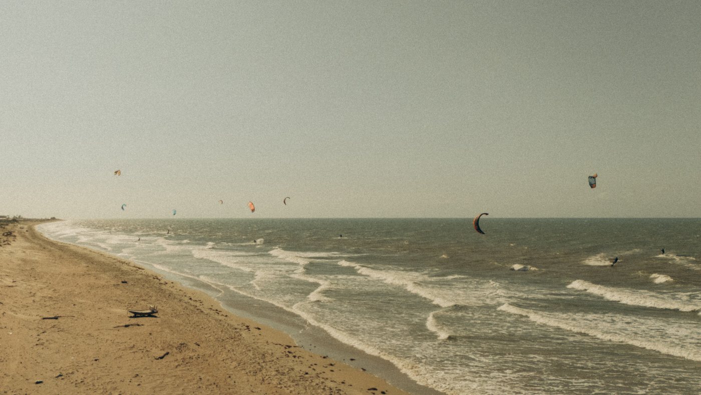 Céu com diversas pipas de kitesurf sobre o mar